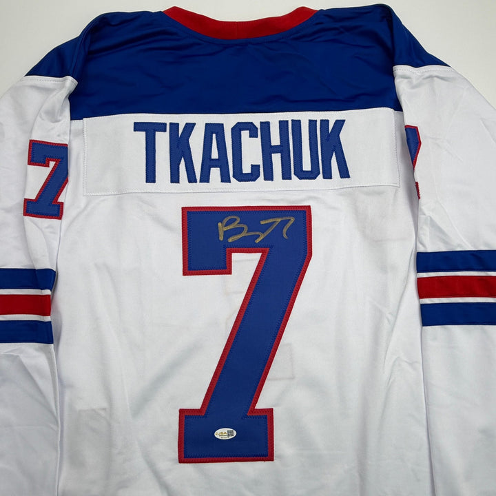 Autographed/Signed Brady Tkachuk USA 2026 Olympics Gold White Jersey JSA COA